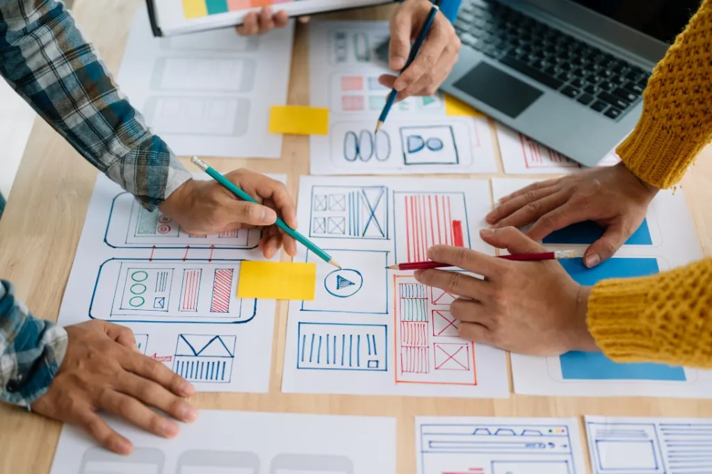 Csapat weboldal wireframe-eket tervez asztalnál papíron és sticky note-okkal